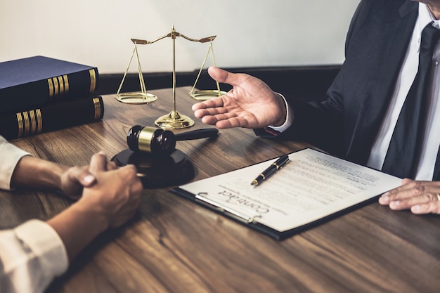 Advogado apresentando um contrato a um cliente, com balança da justiça sobre a mesa